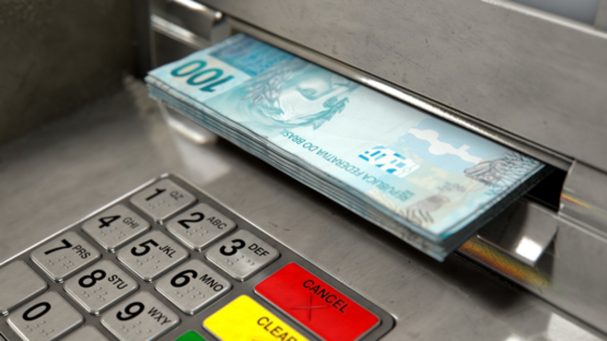 Notas de R$ 100 saindo de caixa eletrônico, em imagem ilustrativa sobre o pagamento dos servidores estaduais